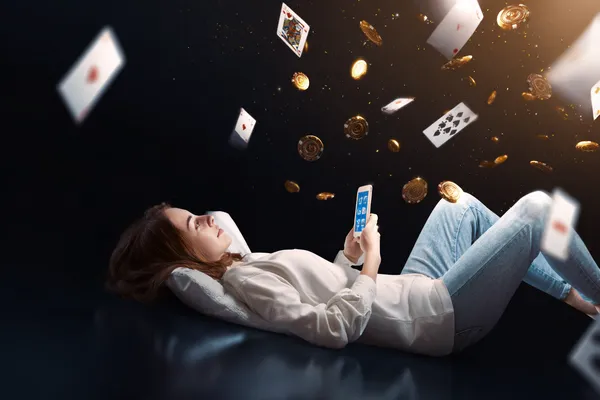 A young woman relaxing with her phone while dynamic casino elements float around her, illustrating the smooth mobile experience offered by the DBKK app.